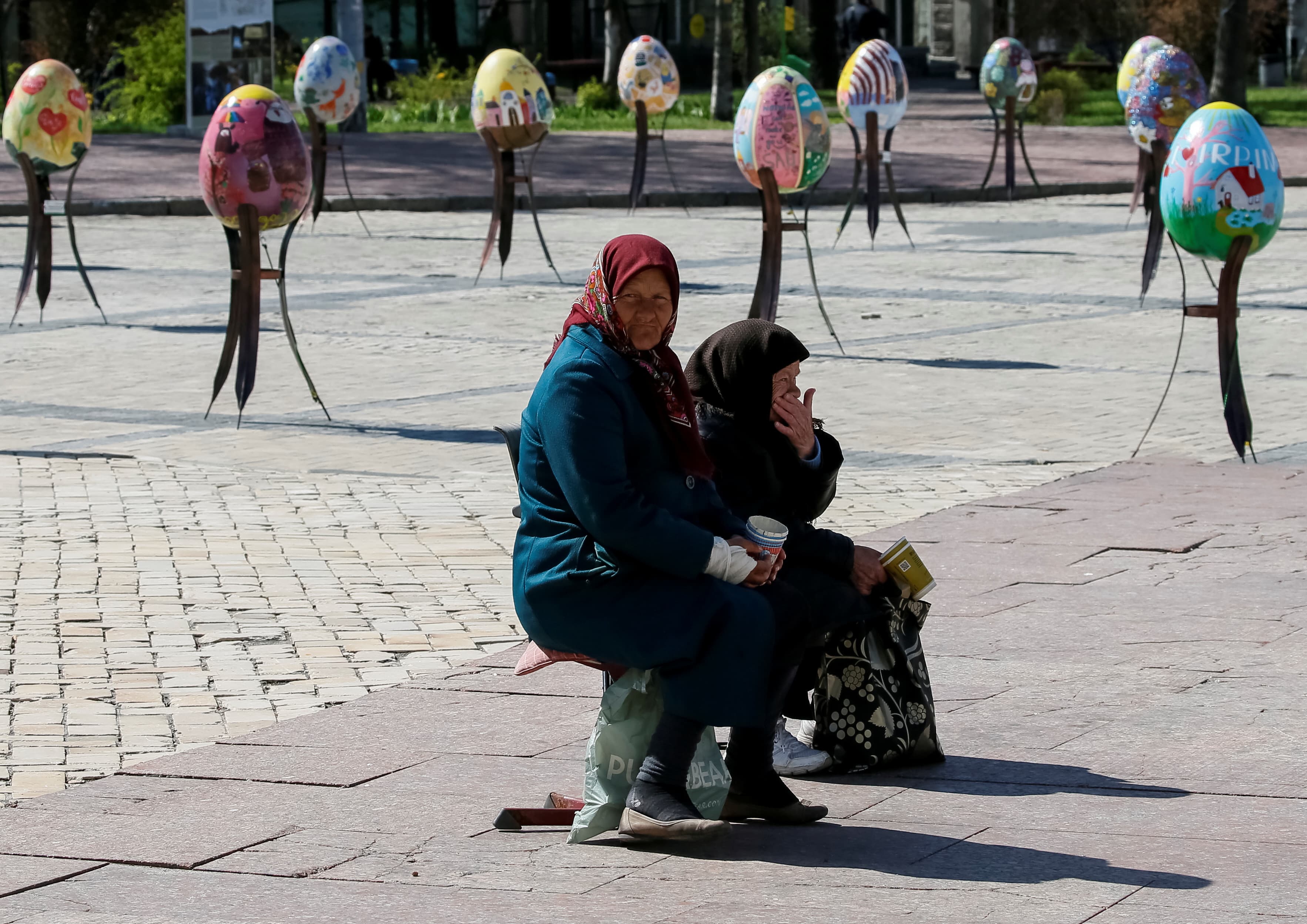 Elderly women beg for money near traditional Ukrainian Easter eggs "Pysanky."