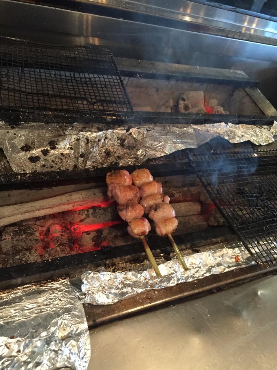 Chicken thighs grilling over binchotan charcoals