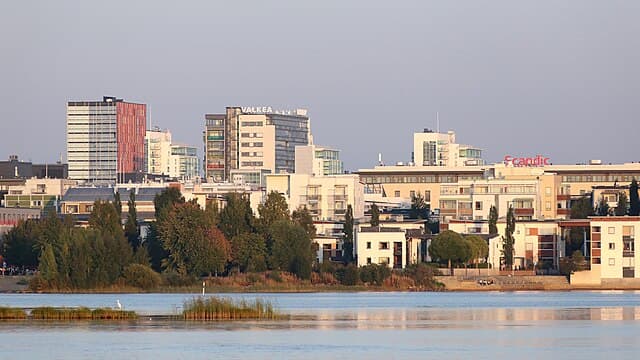Urban skyline with modern high-rise buildings and a tranquil body of water in the foreground.