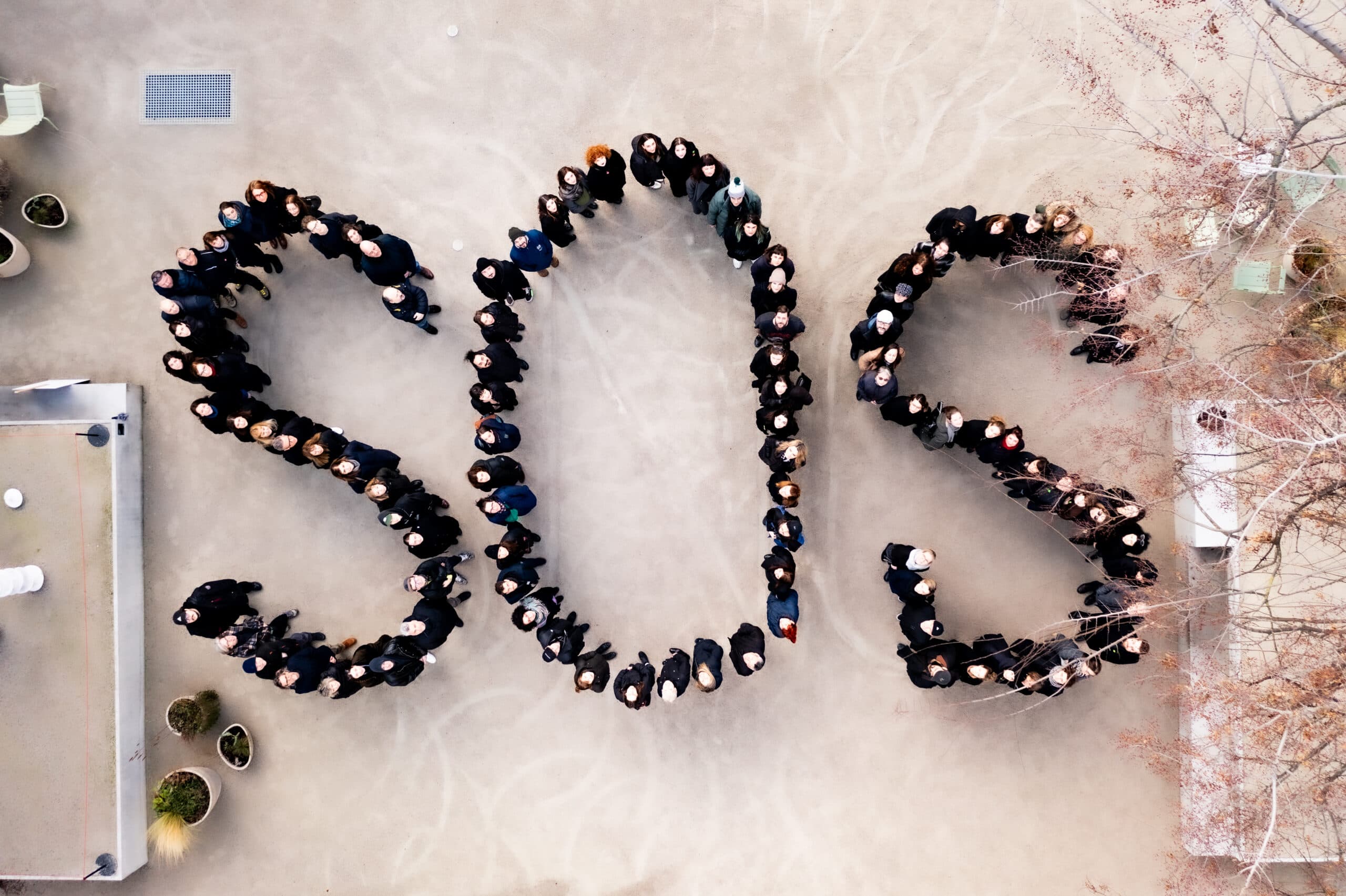 Aerial view of a group of people standing on a concrete surface, forming the letters "SOS".