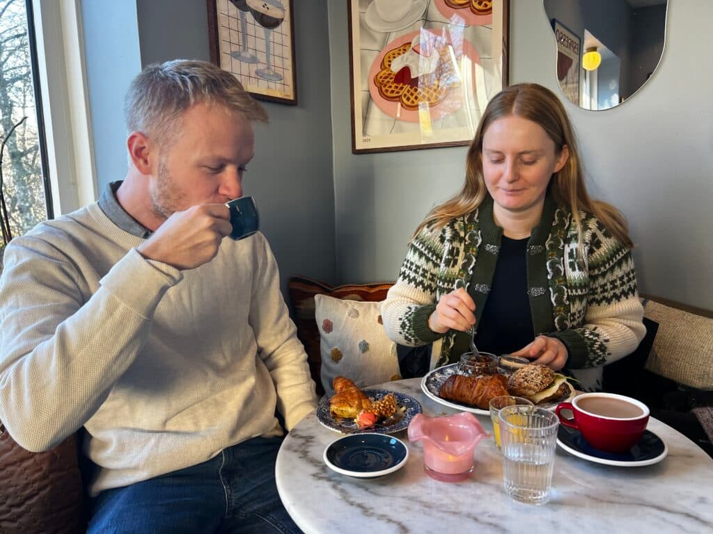 Two people sitting at a café table enjoying pastries and coffee.