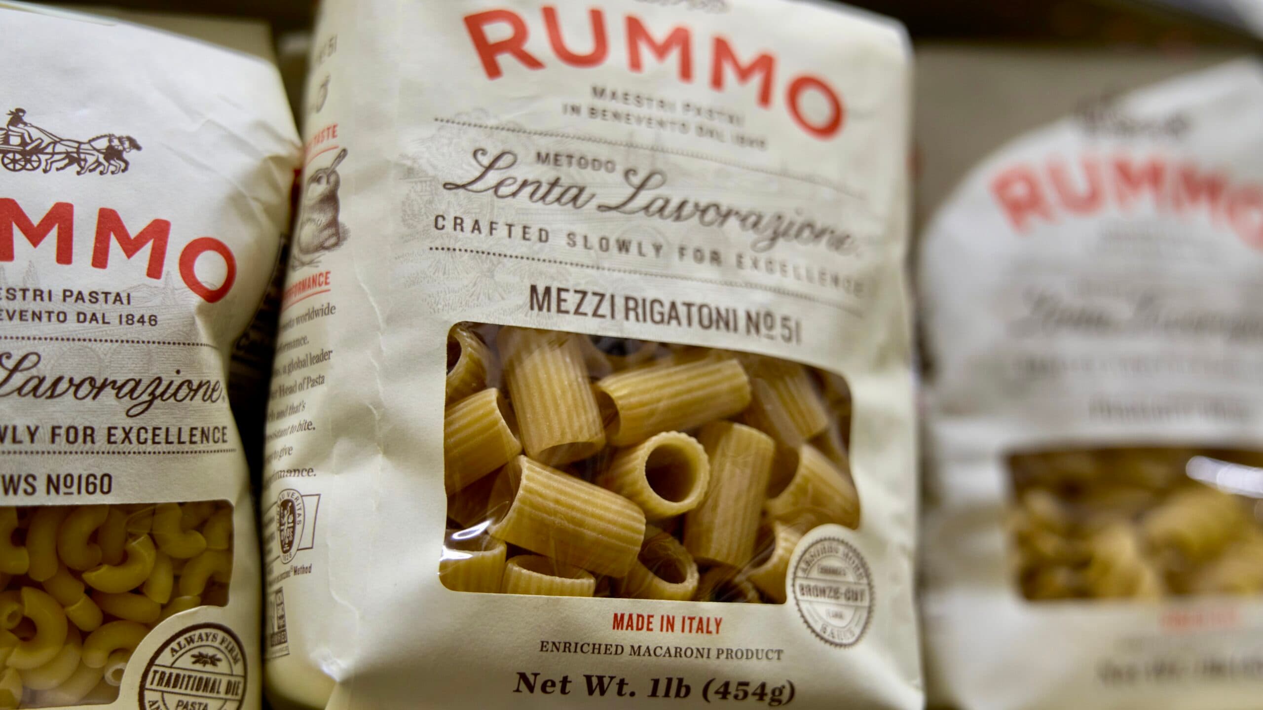 Close-up of Rummo brand pasta packages, featuring Mezzi Rigatoni and other types, with labels indicating the pasta is made in Italy.