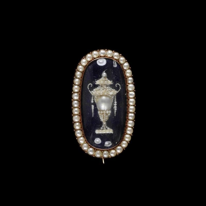 A gold brooch featuring a funeral of enamel, pearls, and hair