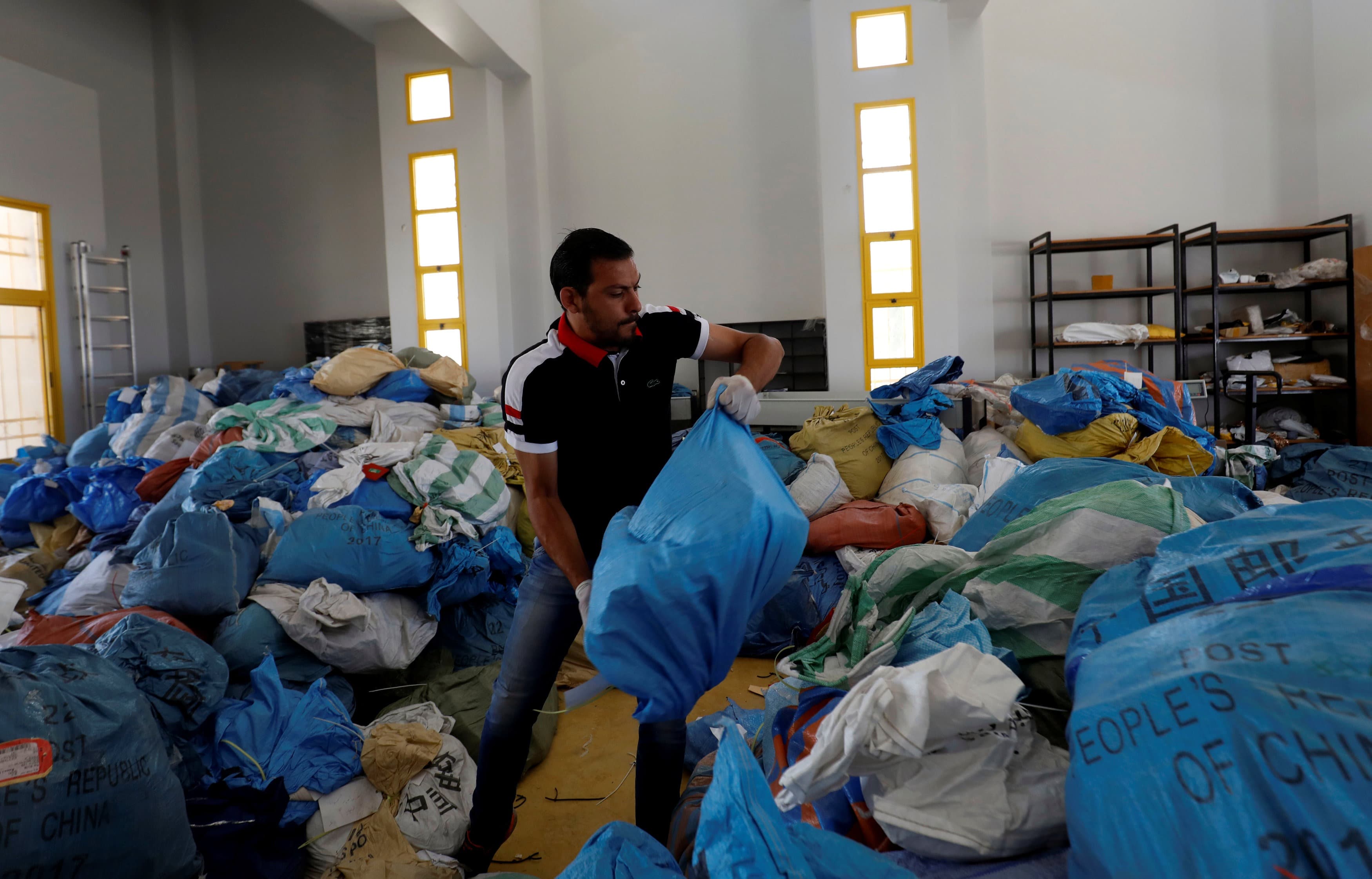 A Palestinian worker carries a bag containing items sent by mail