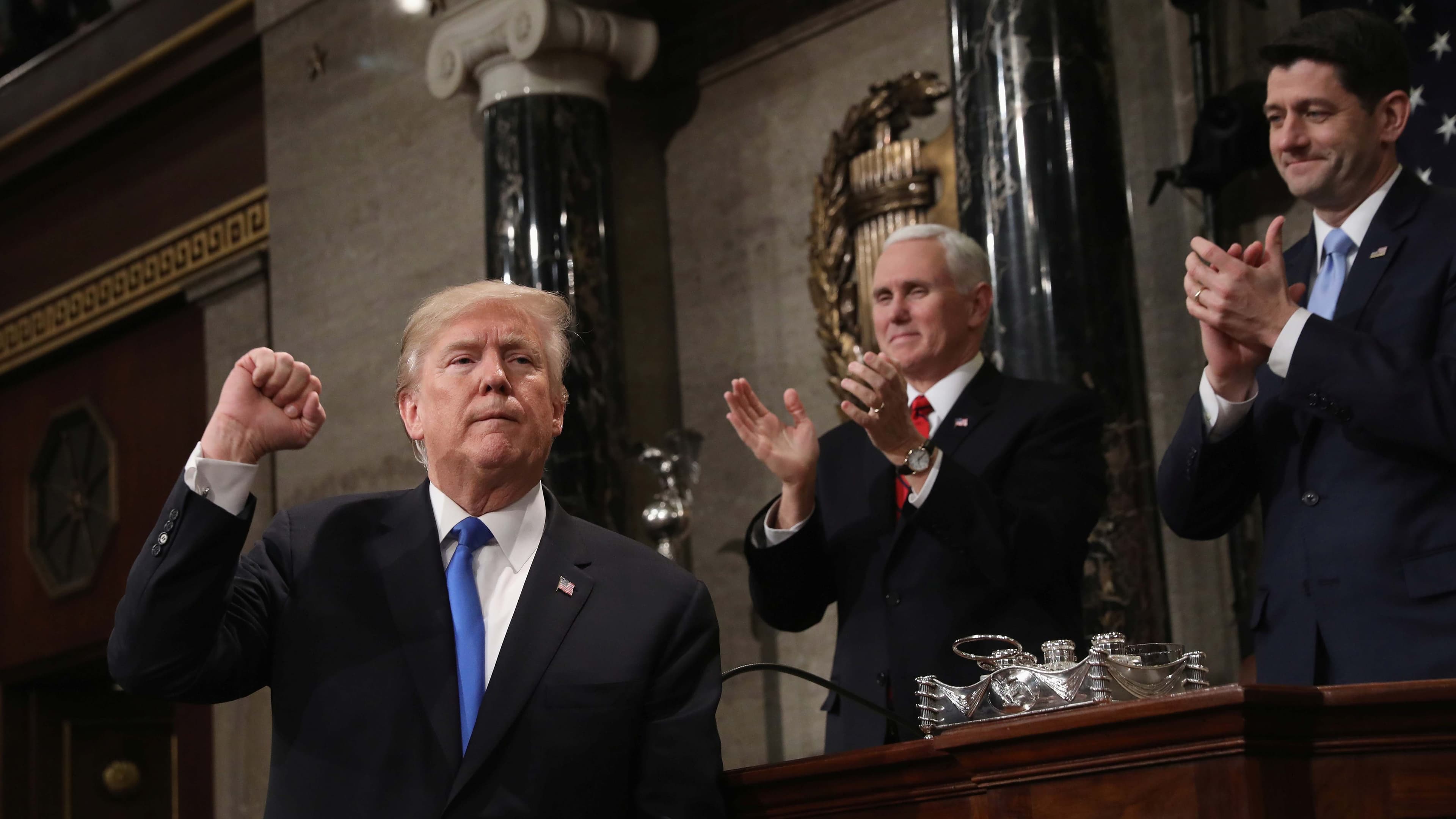 A white man with his first raised, with two white men clapping.