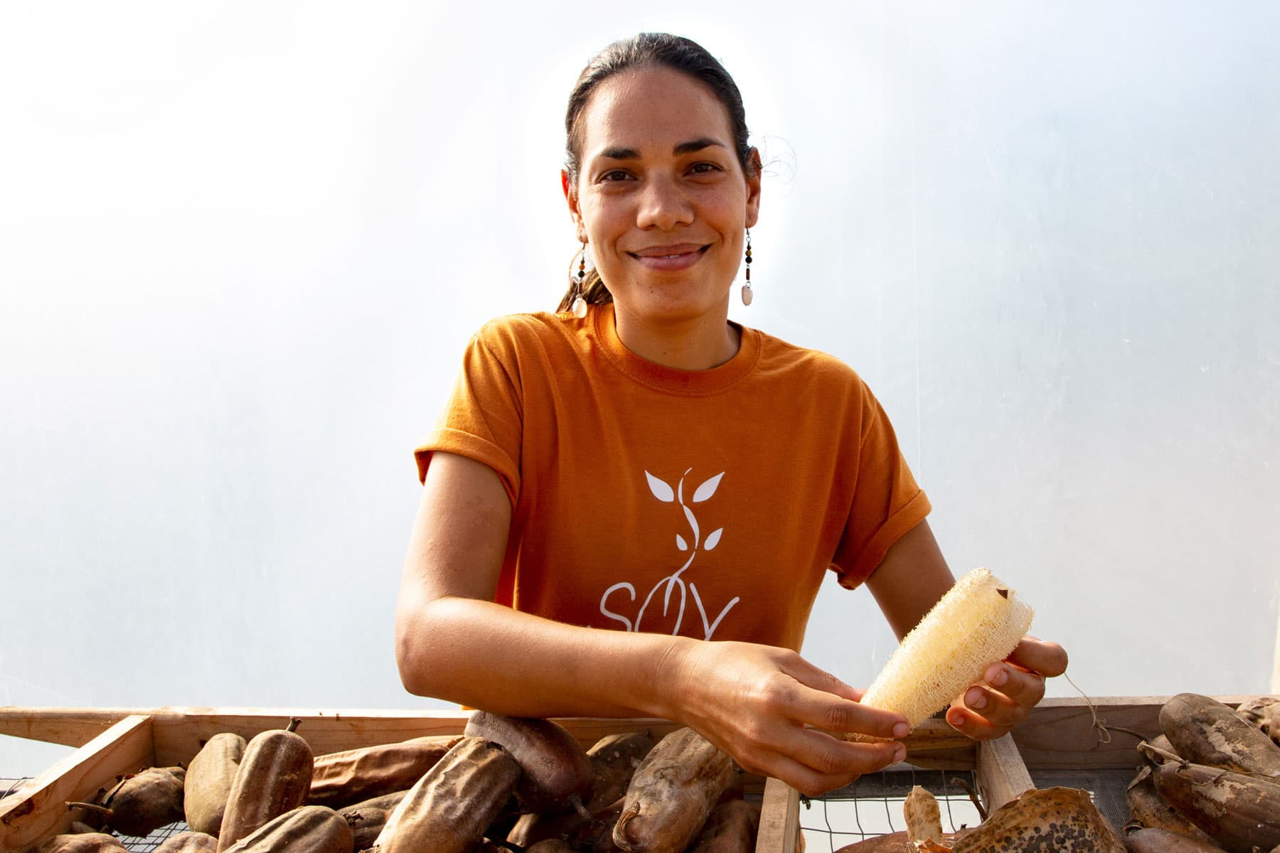 A woman is shown in a portrait photo demonstrating how to remove seeds from a luffa