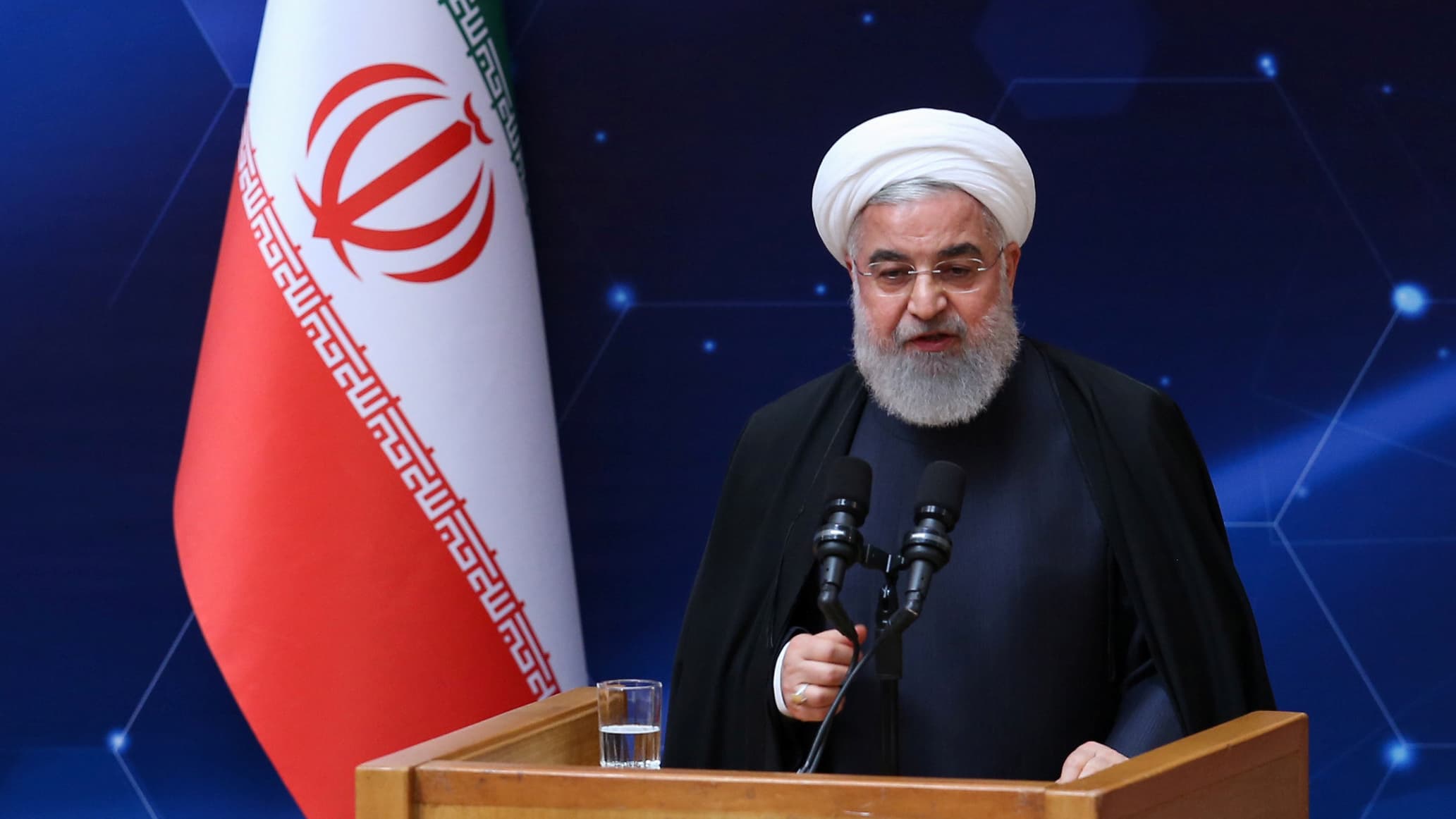 A man stands at a podium with an Iranian flag behind him
