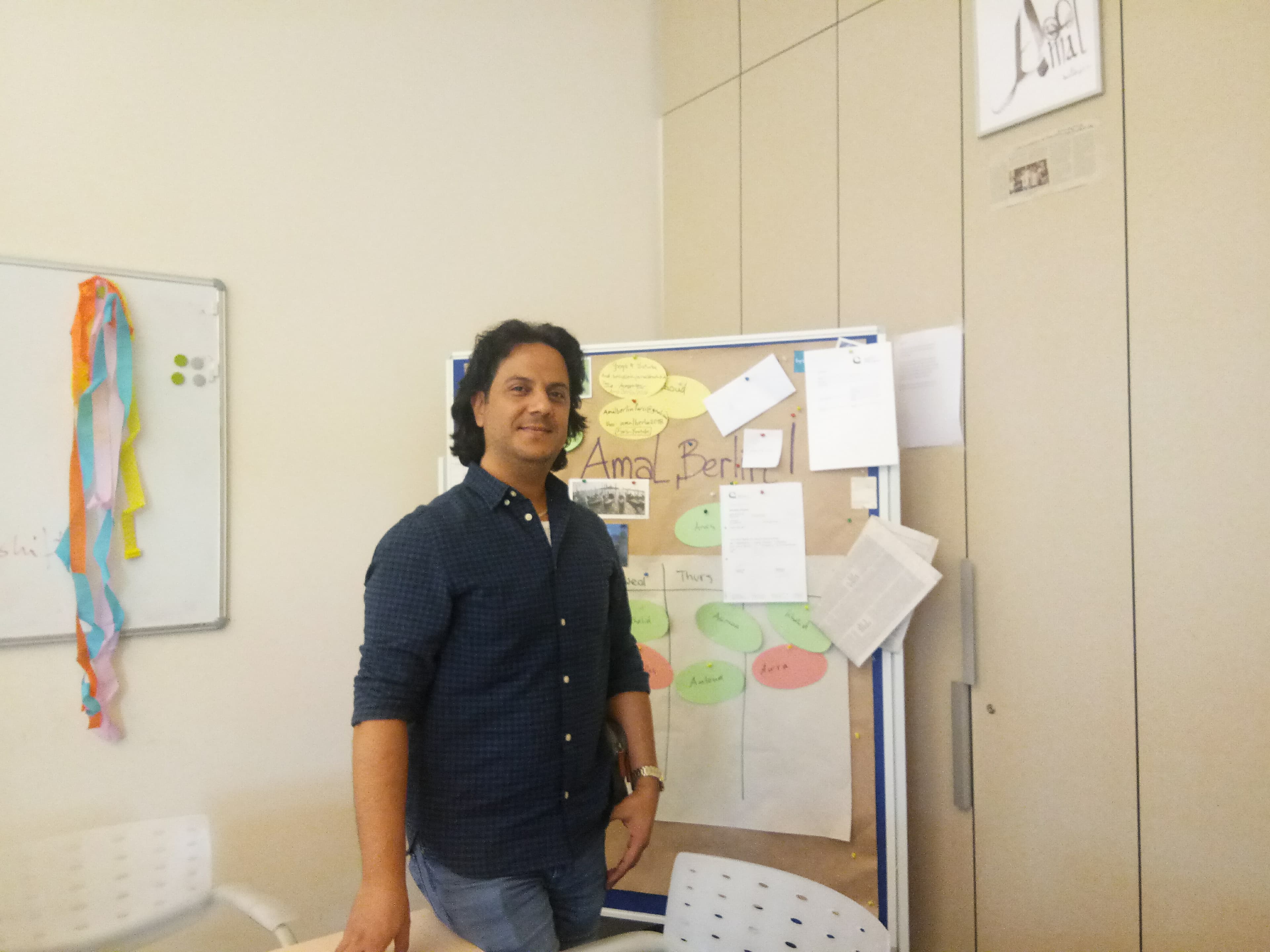 A man stands in a newsroom with a noticeboard behind him.