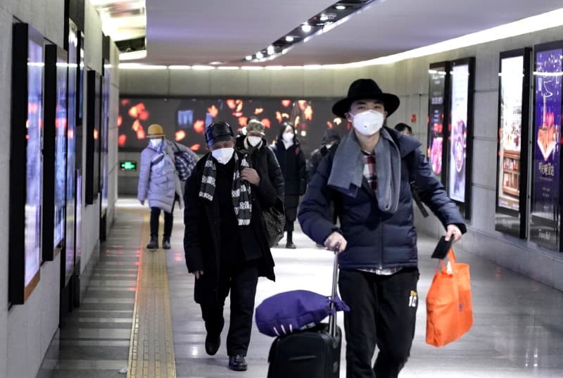 People wearing masks walk through an underground passage to the subway in Beijing, Jan. 21, 2020.