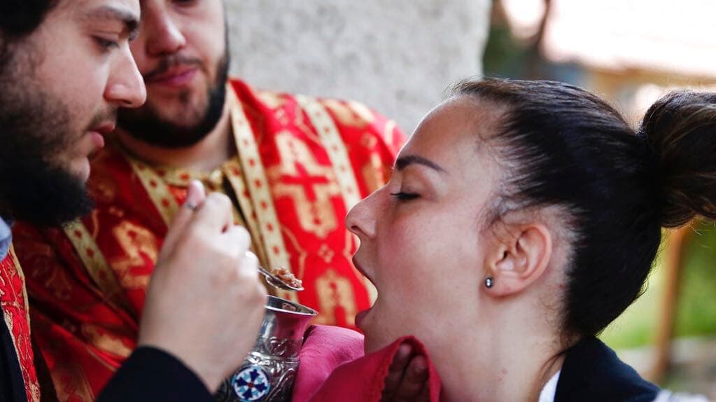 In this Sunday, May 24, 2020, photo, a Greek Orthodox priest distributes Holy Communion during Sunday Mass at a church, in the northern city of Thessaloniki, Greece, using a traditional shared spoon. Contrary to science, the Greek Orthodox Church insists
