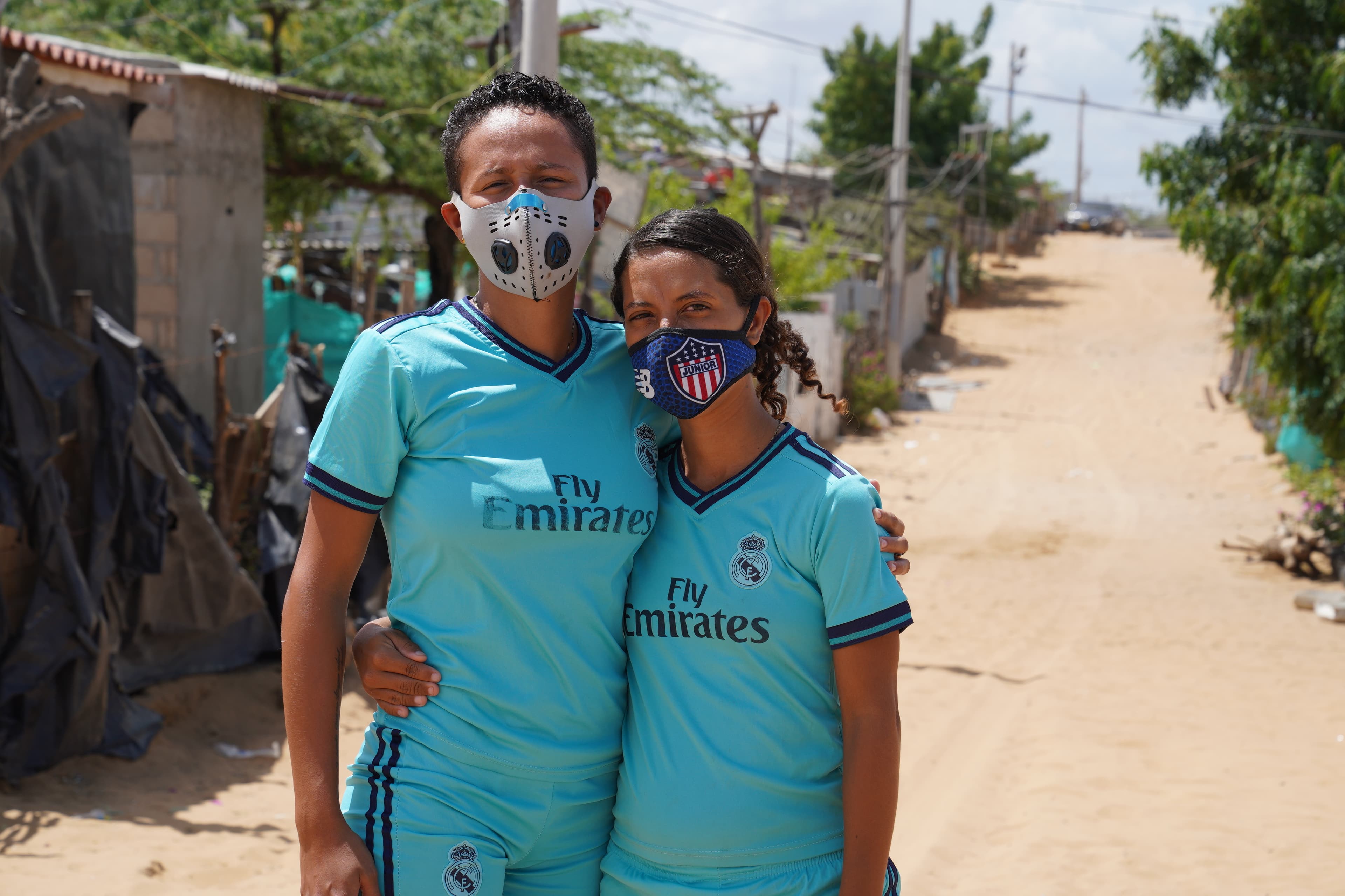 Two kickball players wearing blue uniforms pose for a photo with their arms around each other