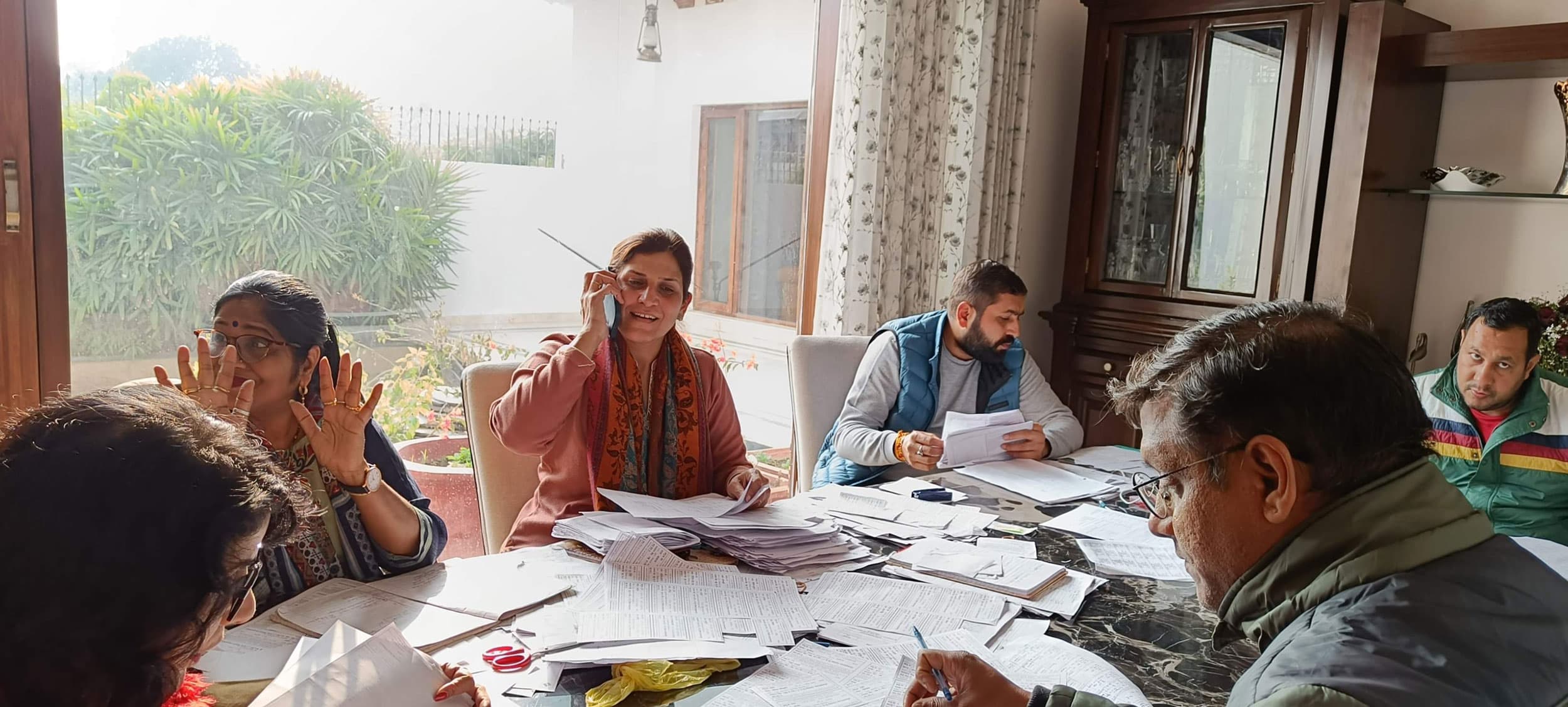 Monika Tewatia’s large dining table is strewn with papers and voter cards.