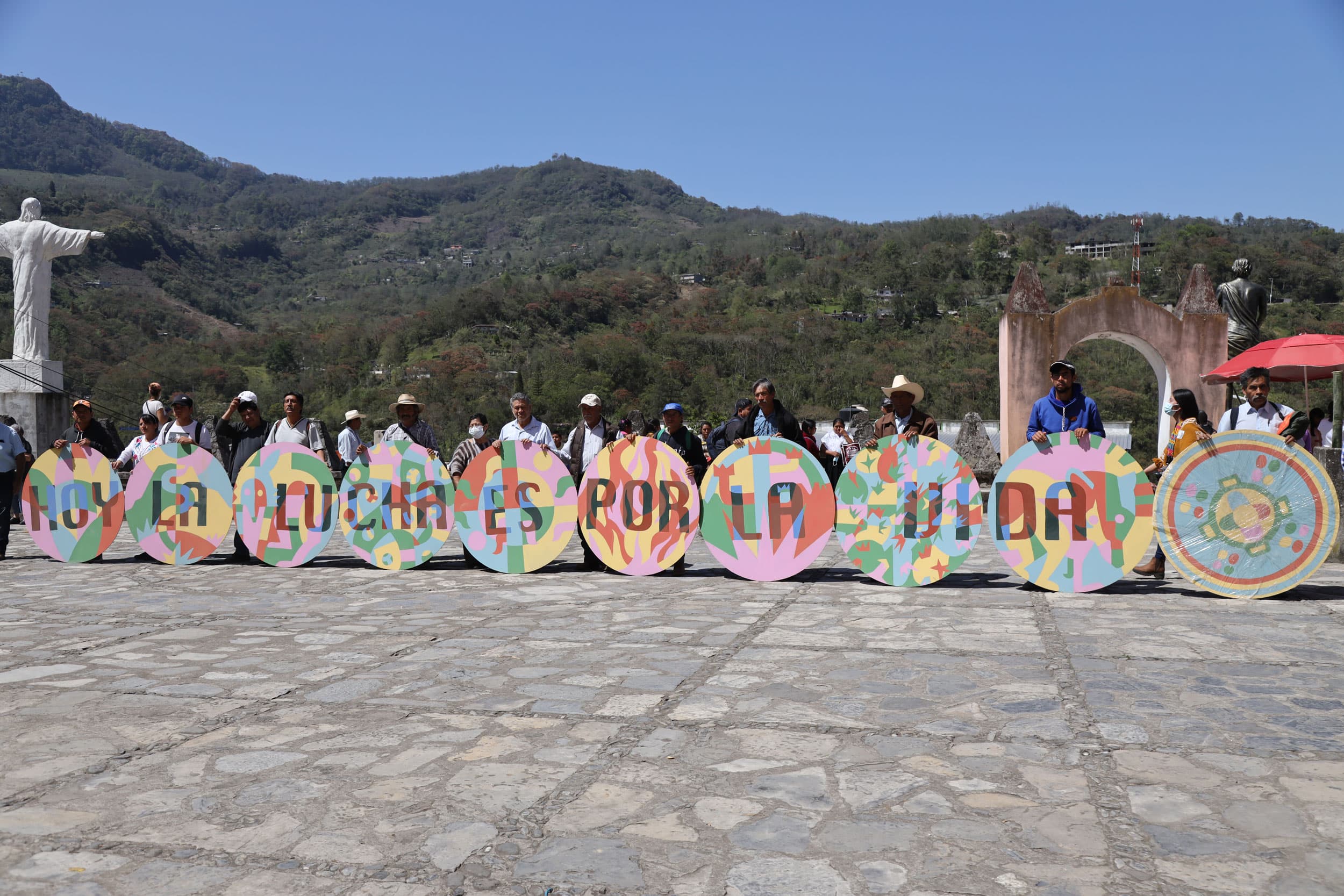 Indigenous activists in Puebla state stand in front of a colorful sign that reads