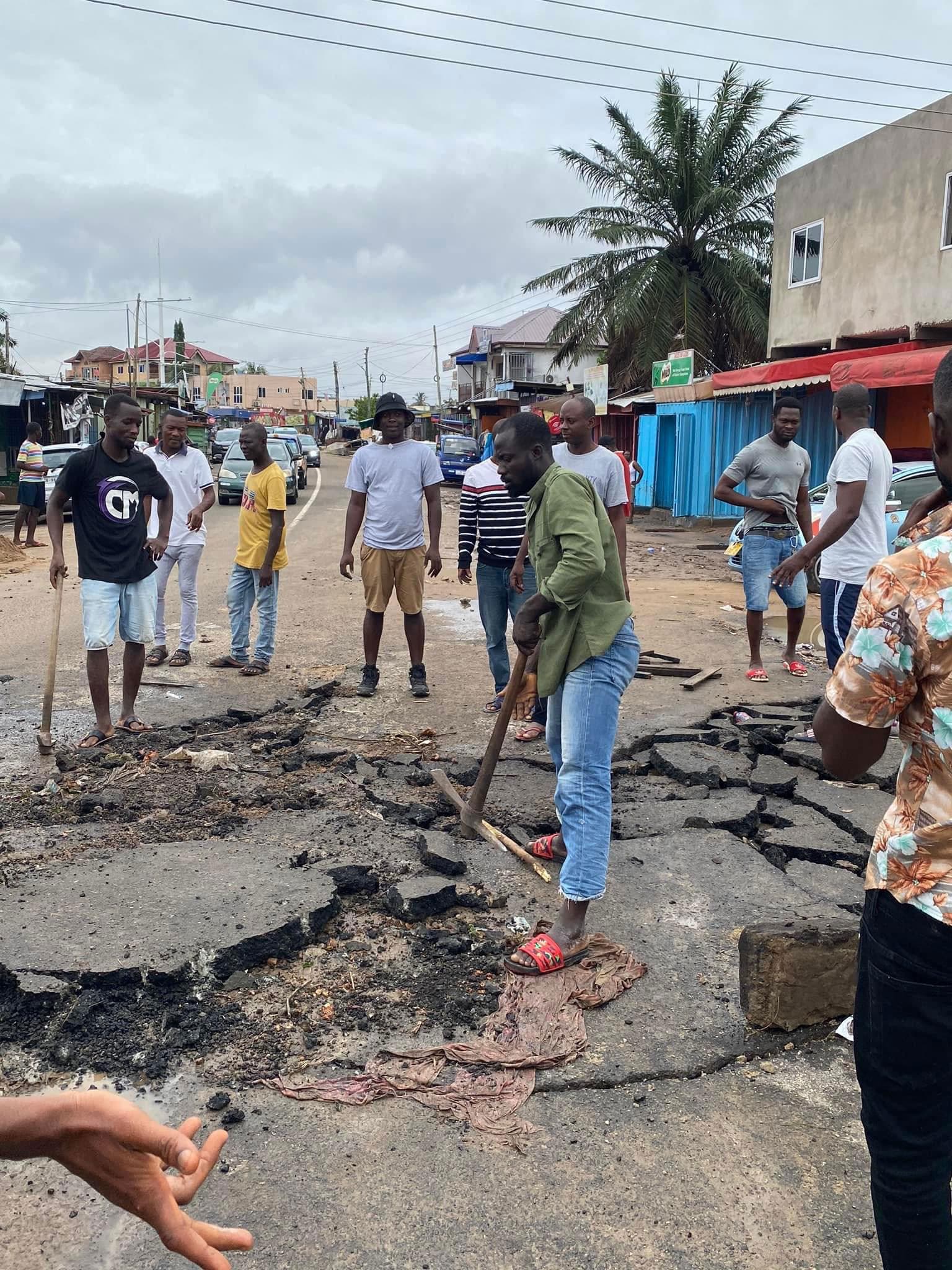 Some residents patch up a road after being destroyed by floodwaters.
