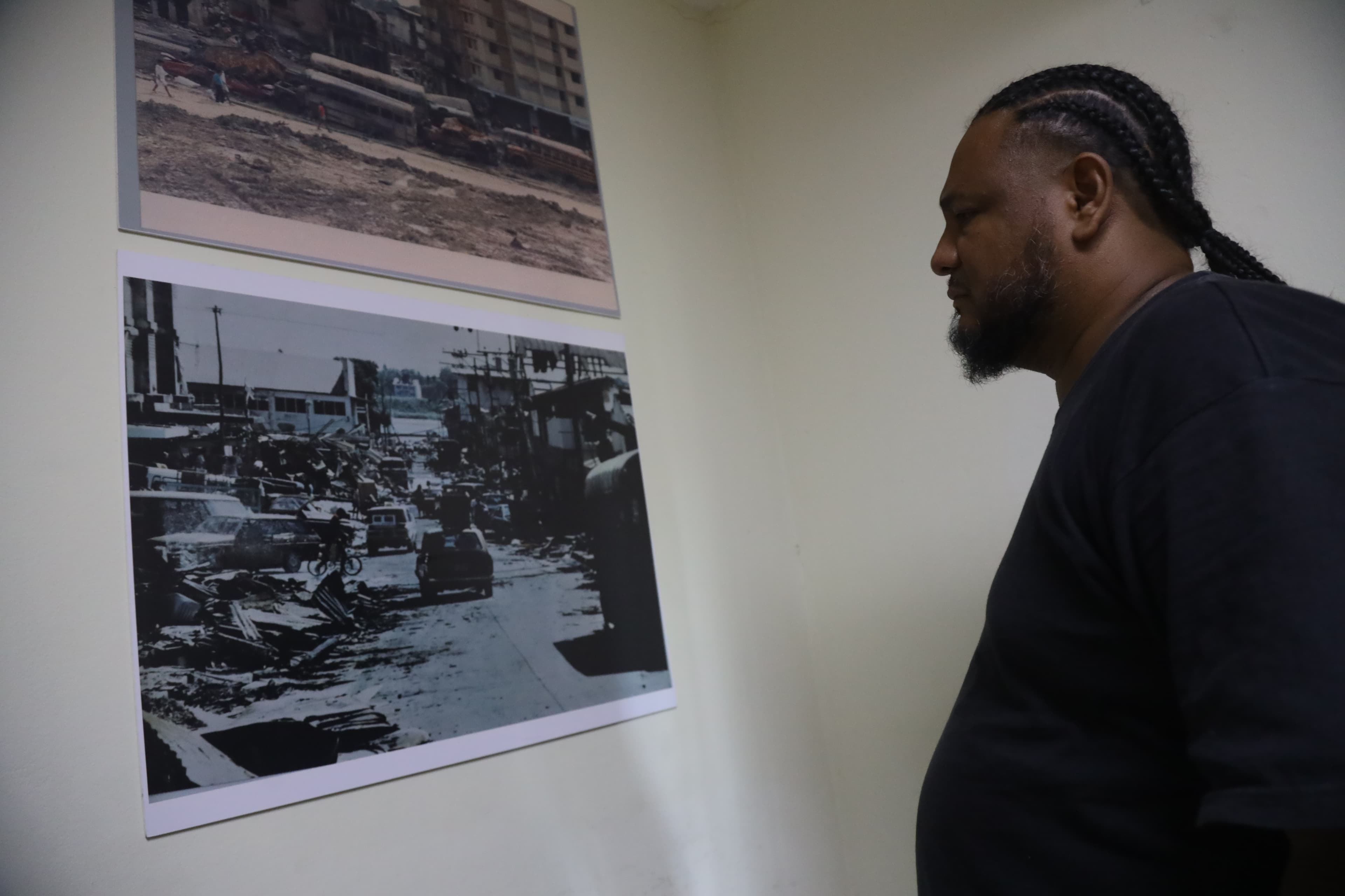 Man looking at black and gray photos on a wall